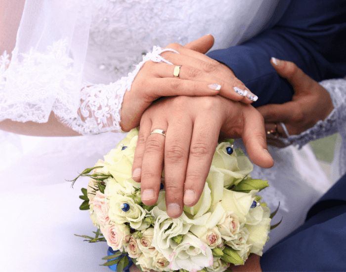 a picture of a bride and a groom's hand's wearing a matching wedding rings.