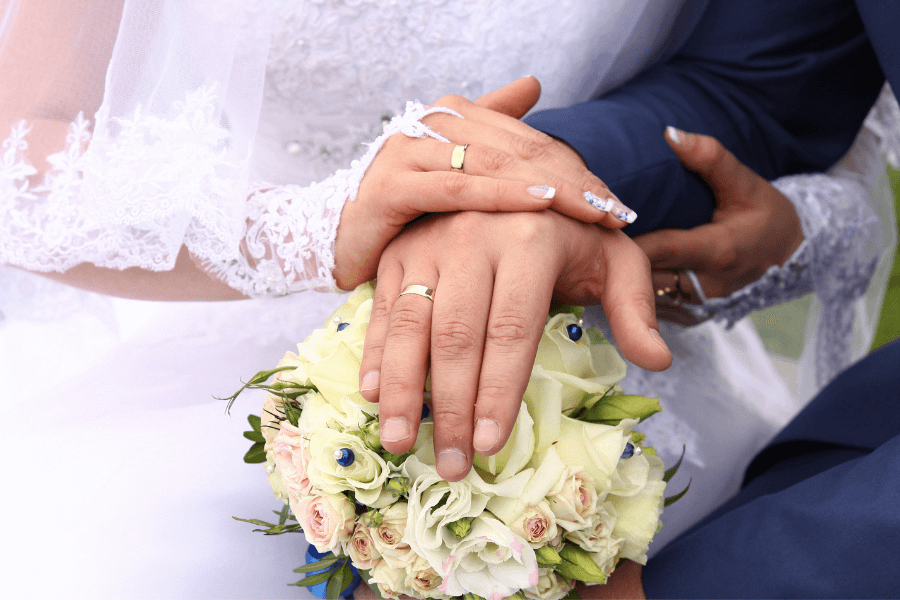 Picture of a bride and a groom's hand's wearing wedding rings