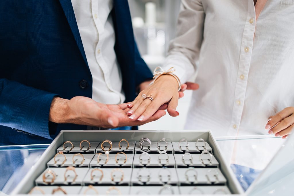 A man holding a woman's hand with gorgeous expensive engagement ring and bracelet at a jewellery store.