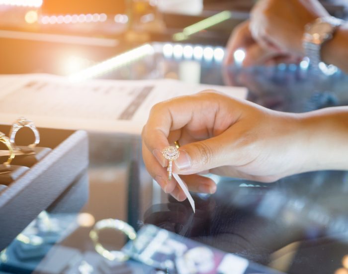 A hand of a woman choosing wedding rings at a jewelry diamond store shop.